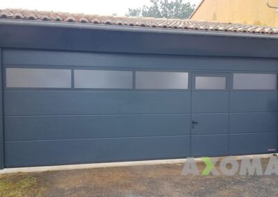 Porte de garage sectionnelle HORMANN grande dimension avec portillon intégré et bande vitrée installée à Treillières